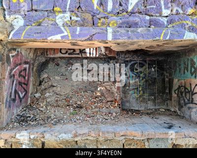 Calpe, Spain - May 27, 2026.A stone fireplace lies in ruins at Club Social La Manzanera. It is filled with brick rubble and covered in colorful graffi Stock Photo