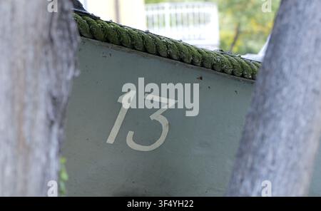 Number 13 painted in white on the side of a worn boat hull, featuring details of a green moss covered rope along the gunwale, framed by blurred backgr Stock Photo