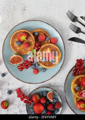 Top view breakfast composition with pancakes, berries and fresh fruit arranged on plates Stock Photo