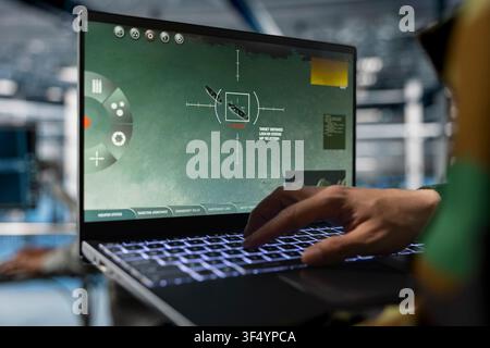 Close up of military officer in data center looking at advanced tracking software identifying moving objects. Soldier in army server hub checking tactical UI showing satellite view on laptop Stock Photo