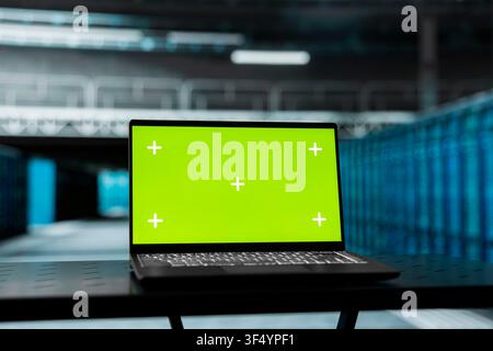 Close up of green screen laptop in data center used to do maintenance on equipment rackmounts. Chroma key device in server hub running software development program, resolving gear failures Stock Photo