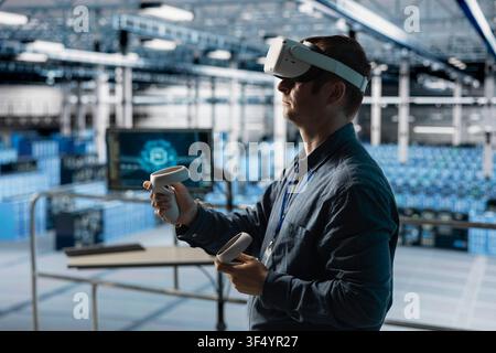 IT expert using VR headset to integrate AI driven automation in data center operations. Data center engineer using virtual reality technology and machine learning to optimize performance Stock Photo