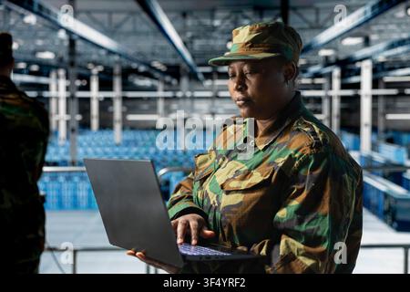 Soldier in server hub doing mission communication systems troubleshooting. African american army information technology expert in data center analyzing system for security breaches Stock Photo