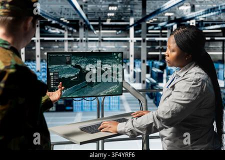 Team of military engineers looking at encrypted satellite intel from classified data center infrastructure. Teamworking server room coworkers extracting enemy movement data using satellite interface Stock Photo