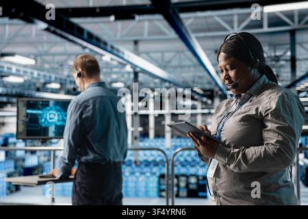 Teamworking data center admins assisting clients with AI troubleshooting, delivering technical support. Server farm coworkers discussing with users in need of assistance using headphones mic Stock Photo