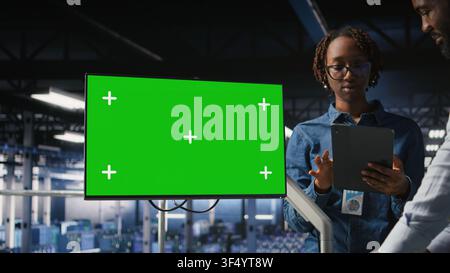 Server room coworkers doing brainstorming, using chroma key device to review diagnostics. Employees doing maintenance tasks in data center, looking at isolated screen monitor, Stock Photo