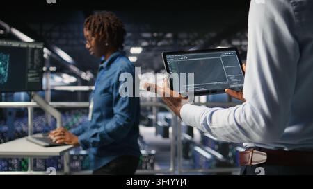Close up of data center programmer looking at code debugging tools running on tablet. Server farm IT professional checking machine learning script automating tasks, Stock Photo