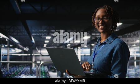 Portrait of joyful computer scientist in data center monitoring neural network LLM visualization. Upbeat woman in server farm overseeing rigs powering machine learning processes, Stock Photo