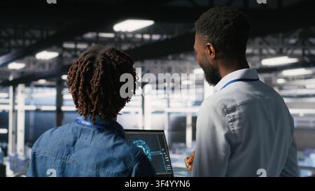 Data center engineering team doing maintenance on rigs handling AI processing tasks. Server hub teamworking colleagues managing storage arrays supporting deep learning training workflows Stock Photo