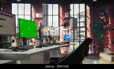 Chroma key computer displays in empty office showing analytics dashboards and data graphs. Office workspace with green screen PCs showing digital data visualization, panning shot Stock Photo