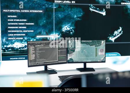 Military command post workstation with computer screens displaying satellite surveillance software. Intelligence system monitors defensive operation data inside empty control room, close up Stock Photo