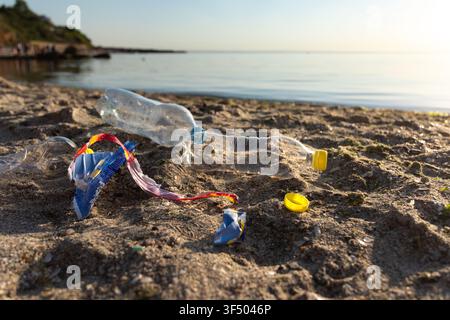 Polluted Beach With Plastic Garbage Lying On Sand Near Water Stock Photo