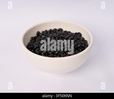 Ceramic bowl filled with dried black beans isolated on white background Stock Photo
