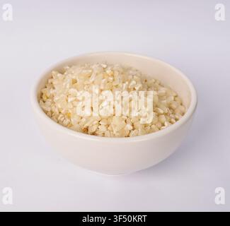 Coarse cracked corn in a white ceramic bowl isolated on white background Stock Photo