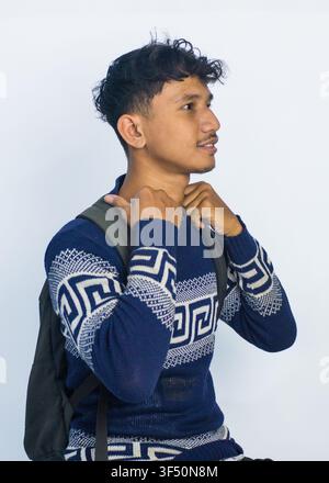 A high-quality profile portrait of a confident young Southeast Asian man wearing a navy blue patterned sweater and carrying a backpack Stock Photo