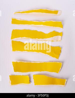 Horizontal rows of torn yellow paper strips isolated on white background Stock Photo