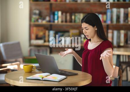 Confused Asian Woman Having Problems With Laptop While Working Remotely In Cafe Stock Photo