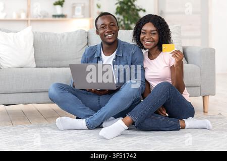 Excited married couple with laptop buying furniture online Stock Photo