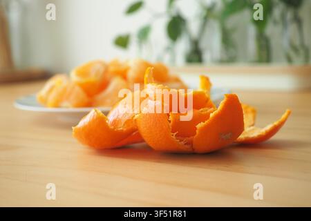 Peels of oranges on a wooden table with more oranges Stock Photo