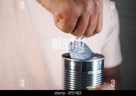 Opening a can in a kitchen with a can opener Stock Photo