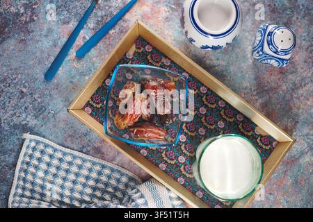 Dates and milk on tray with blue utensils and tablecloth Stock Photo