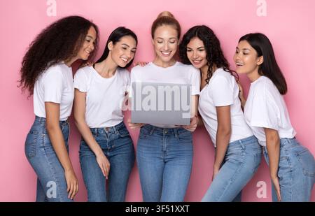 Group Of Multiracial Women Using Laptop Standing Over Pink Background Stock Photo