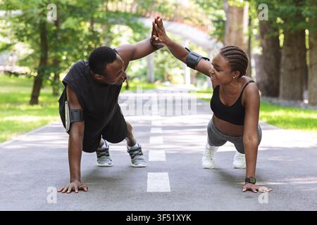 Motivated black couple giving high-five to each other while working out outdoors Stock Photo