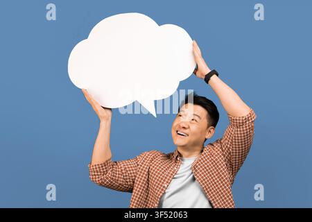 Smiling Asian Man Holding Blank Speech Bubble Overhead, Copy Space, Communication Concept Stock Photo