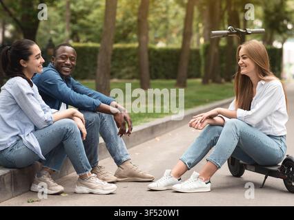 Happy Multiracial Friends Smiling And Relaxing Together In Park, Socializing And Enjoying Day Stock Photo