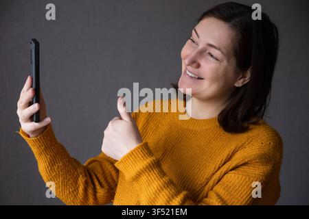 Pregnant woman smiling while taking a selfie with a smartphone Stock Photo