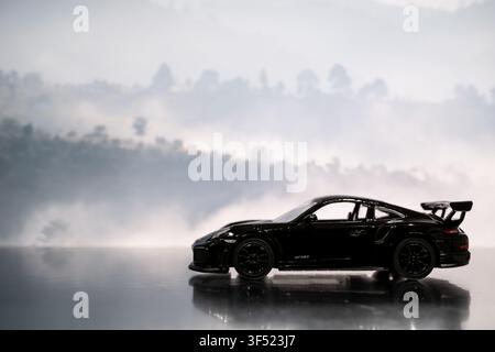 Chiang Mai, Thailand - 28 July 2026 : Black Porsche 911 GT2 RS diecast model car side view, dense foggy mountain background Stock Photo