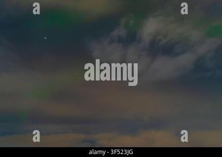 Spectacular green Aurora Borealis northern lights glowing in the starry night sky with dramatic clouds Stock Photo