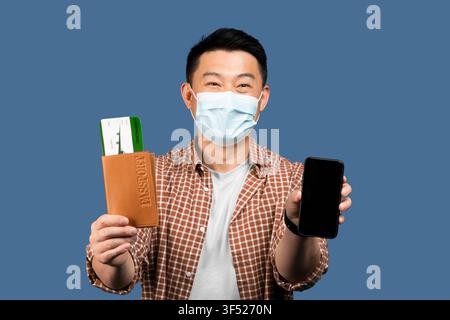 Happy Asian Male Holding Passport And Smartphone, Ready For Travel, Studio Background Stock Photo