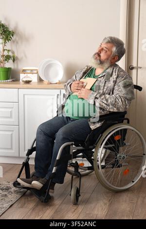 Portrait of sad senior veteran in wheelchair with letters at home Stock Photo