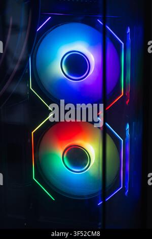 Vibrant RGB fans glow inside a gaming PC case behind tempered glass, showcasing colorful LED lighting, cooling hardware and futuristic design ideal fo Stock Photo