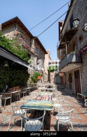Empty restaurant tables for al fresco dining set between historic stone buildings in Taormina, Sicily Stock Photo