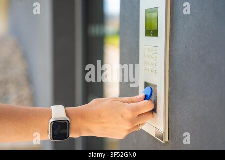Person using contactless key fob on residential building access control system. Secure entry technology supports convenient and controlled property Stock Photo