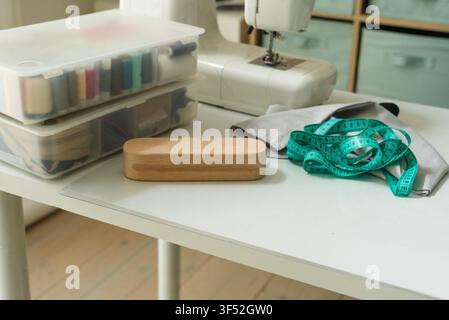 Pressing board for ironing seams and a sewing machine with fabric on a table for professional steam preparation. Tailor board used as a precise pressing tool in a home studio with natural light. Stock Photo