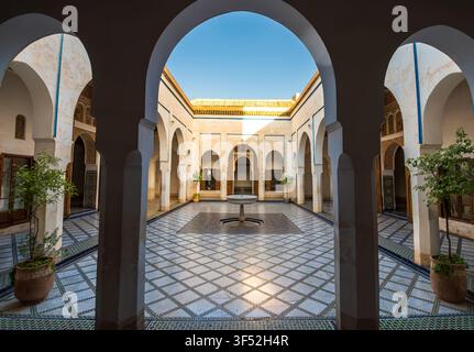 Beautiful symmetrical courtyard inside Bahia Palace in Marrakech, Morocco, featuring traditional Moroccan arches, intricate architecture, tiled floor, Stock Photo
