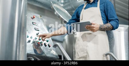Man With Tattoo Operating Control Panel In Industrial Setting, Focused On Work Process Stock Photo