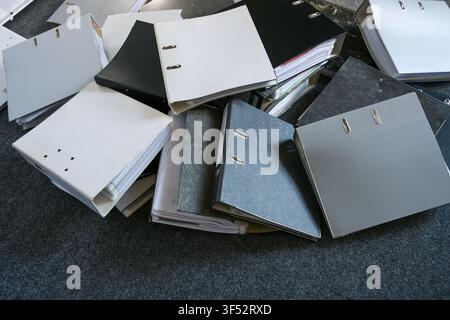 Lots of ring binders are scattered on a gray carpet in the office, symbolizing excessive bureaucracy and business record-keeping requirements, top vie Stock Photo