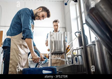 Two Young Men Working Together In Kitchen Preparing Food, Focused Action, Business Concept Stock Photo