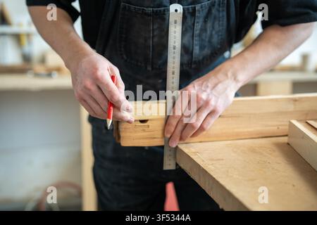 Craftsman working in restoration studio on reconstruction of aged wooden window frame details. Stock Photo