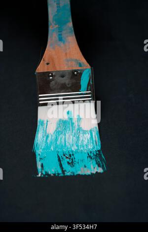 Brush with blue oil paint on the dark background. Stock Photo