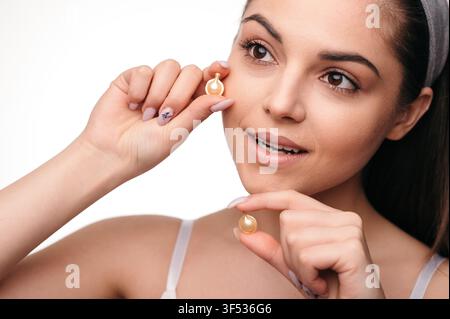 Brunette Woman Applying Skincare Capsule Stock Photo