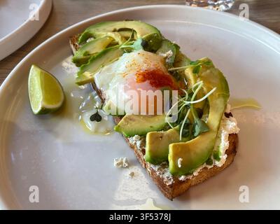 Fried egg with avocado, cheese cream and paprika on toast. Stock Photo