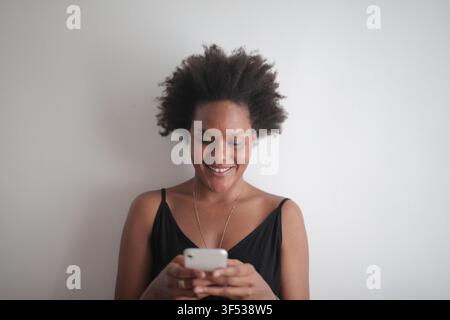 Happy woman with natural hair using her smartphone Stock Photo