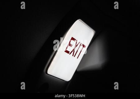 A bright EXIT sign illuminates a dark space. Stock Photo