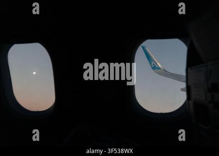 A view from inside an airplane window showing the wingtip and sky. Stock Photo