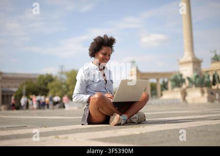 Happy young woman working on laptop in Budapest Stock Photo